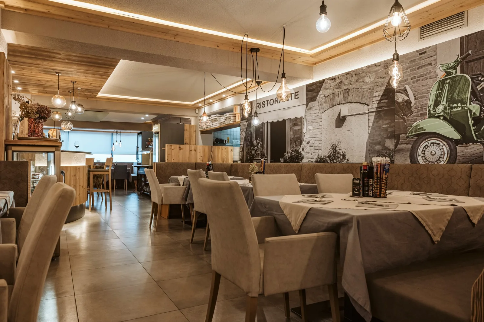 Restaurant mit Holzdecke, Lichtfugen, Glühbirnen-Pendeln und einem Wandbild mit Motorroller