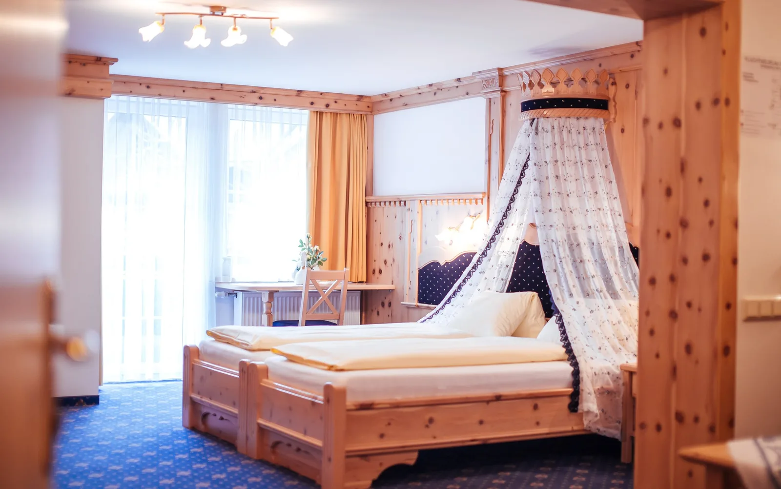 Schlafzimmer mit Holzvertäfelung und Himmelbett mit Krone