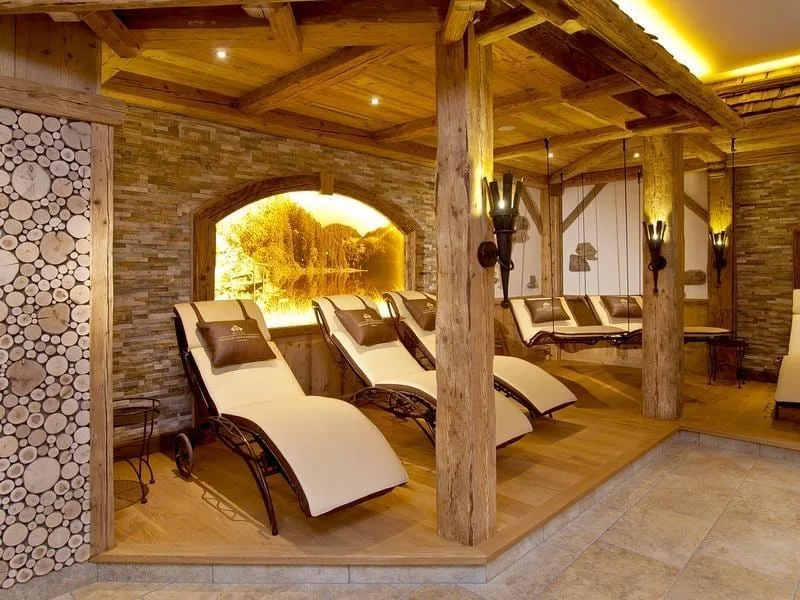 Ruheraum mit Holzbalken, einer Wand aus Holzscheiben und hellen Liegen