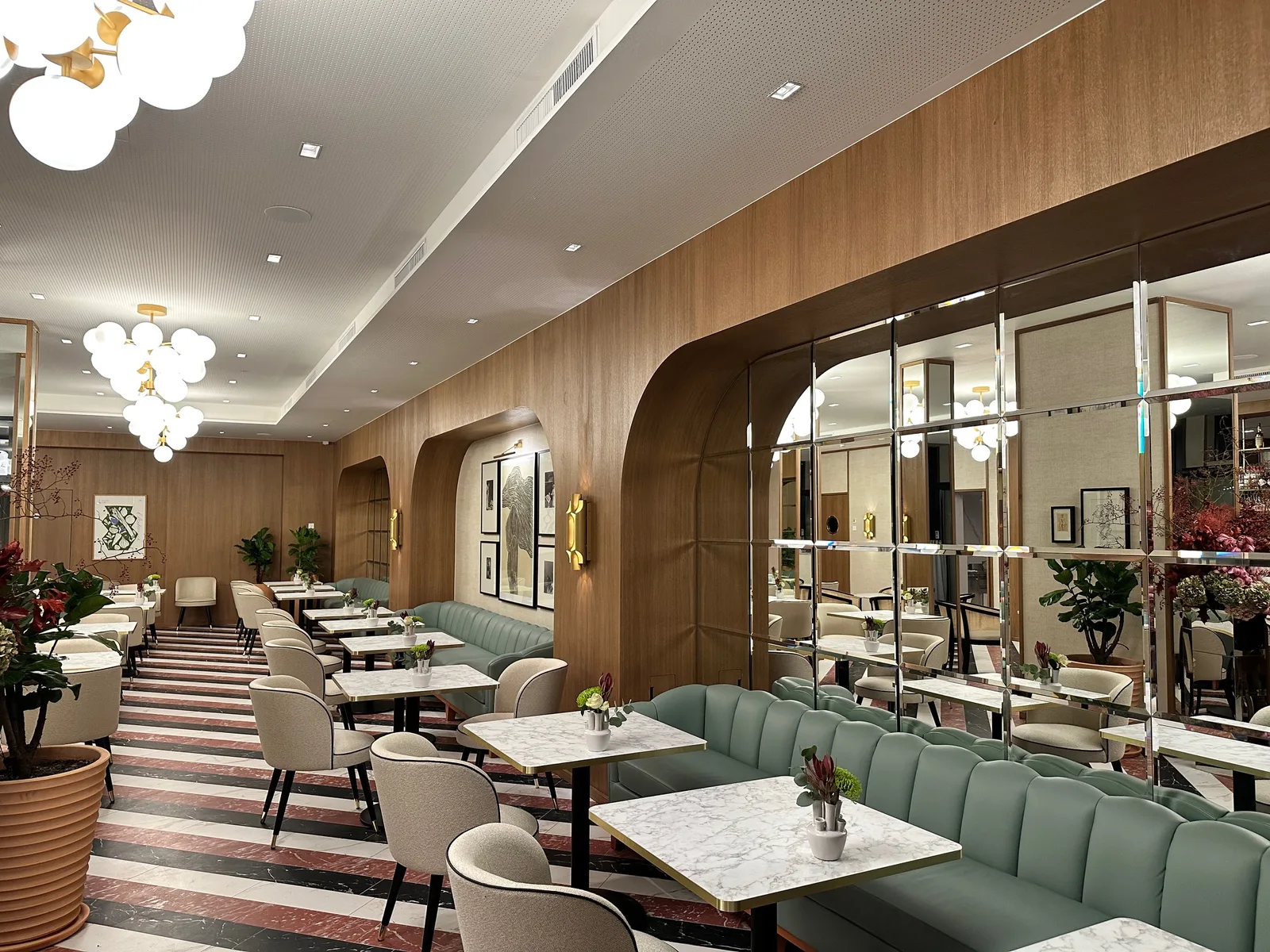Restaurant mit Wandvertäfelung aus Holz, Rundbögen, Spiegelwand und grüner Polsterbank